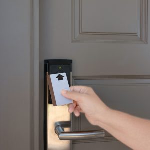 hand holding keycard to scan electronic lock door in order to open the door