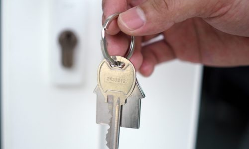 The hand of the banker holds the house key. Home and land mortgage concept